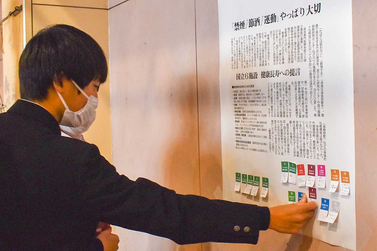 記事の拡大コピーにふせんを貼り替える生徒たち